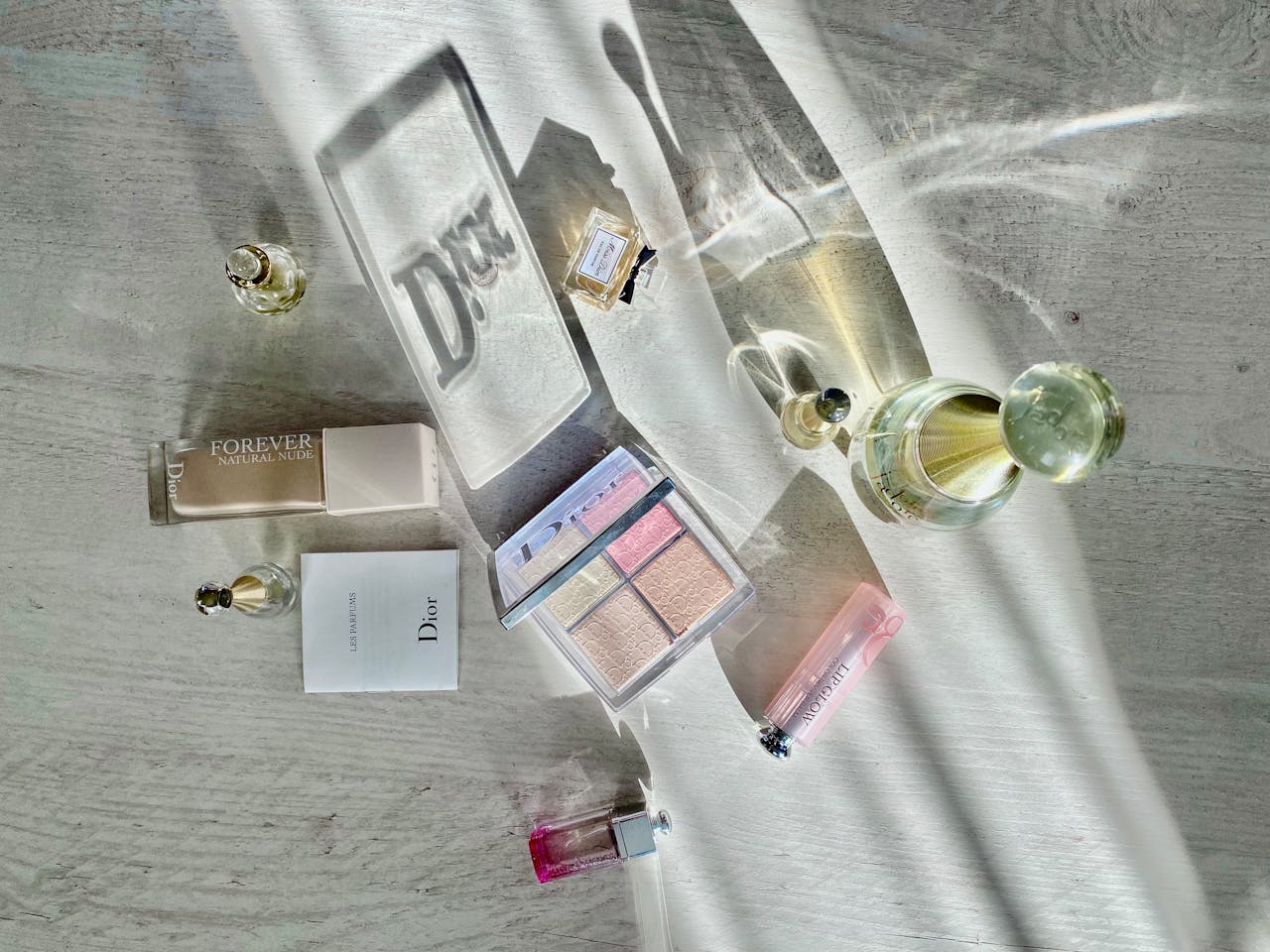 Zapachowa garderoba: Dlaczego jeden flakon perfum to za mało? High-angle shot of Dior cosmetics and perfumes casting artistic shadows.