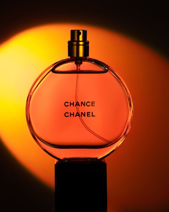 Elegant still life of Chanel Chance perfume bottle against vibrant orange background.