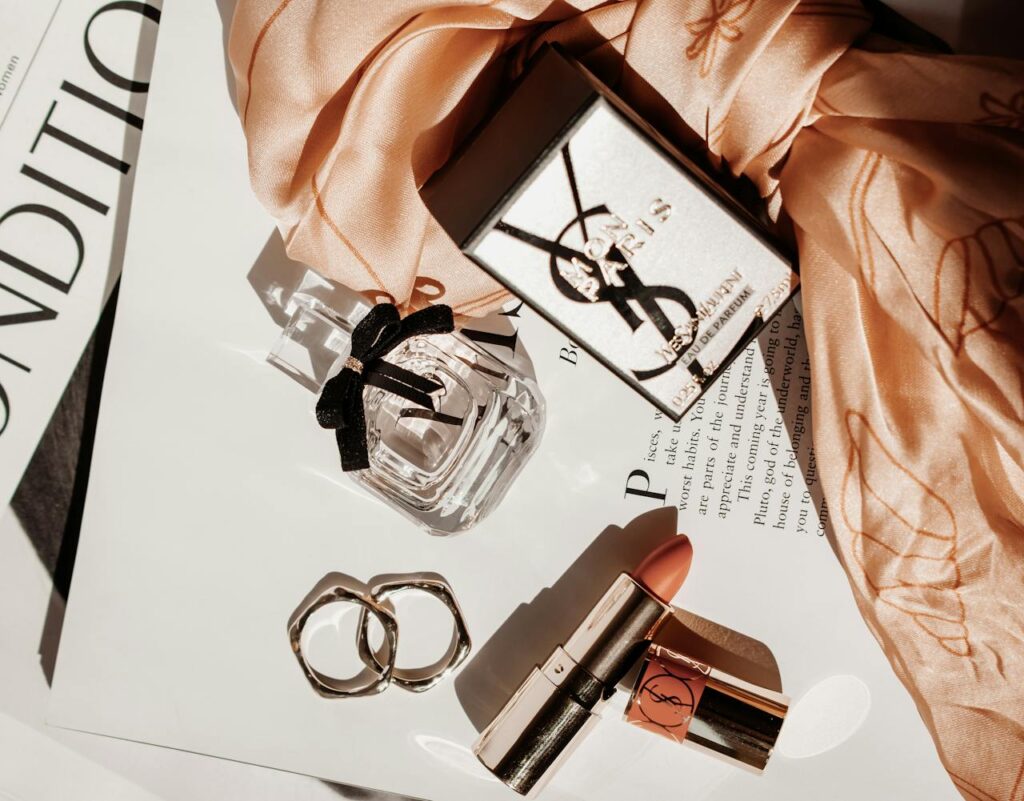 Sophisticated flat lay featuring luxury beauty products, including perfume and lipstick, with a stylish scarf.