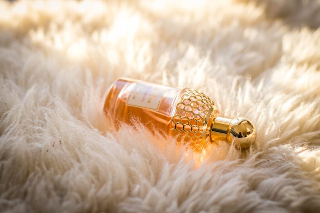 pexels photo 965992 Elegant perfume bottle with gold details resting on fluffy white fur, capturing luxury and glamour.