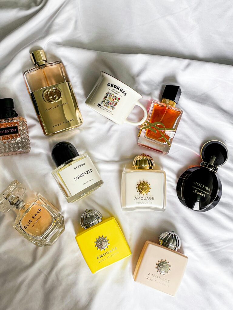 Flat lay of various luxury perfume bottles on a soft fabric background.